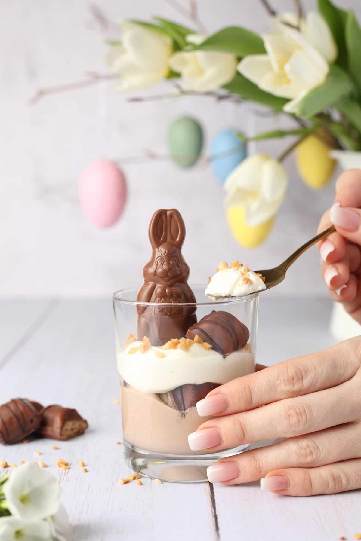 Two hands scooping a bite of creamy Bueno dessert out of a glass jar.