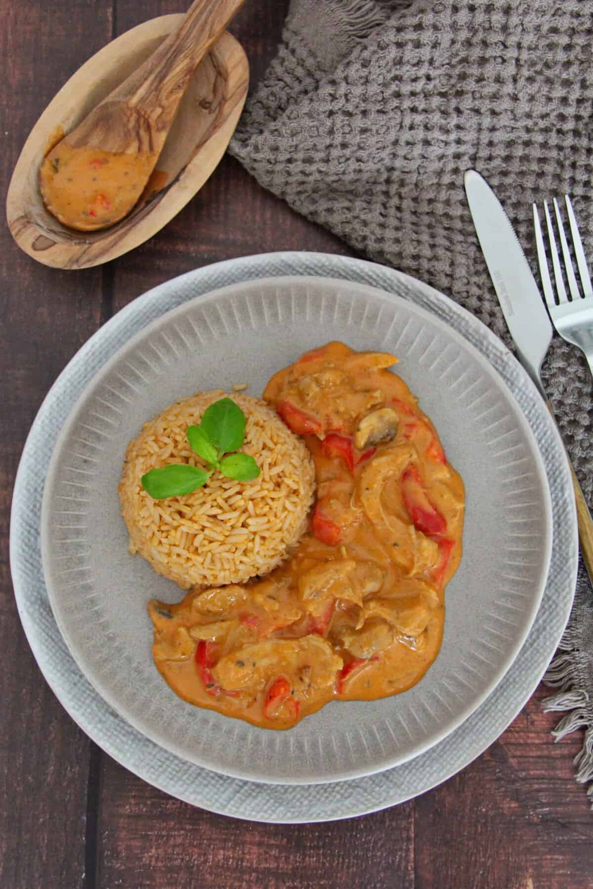 A plate of chicken gyros strips with bell peppers, mushrooms, and rice.