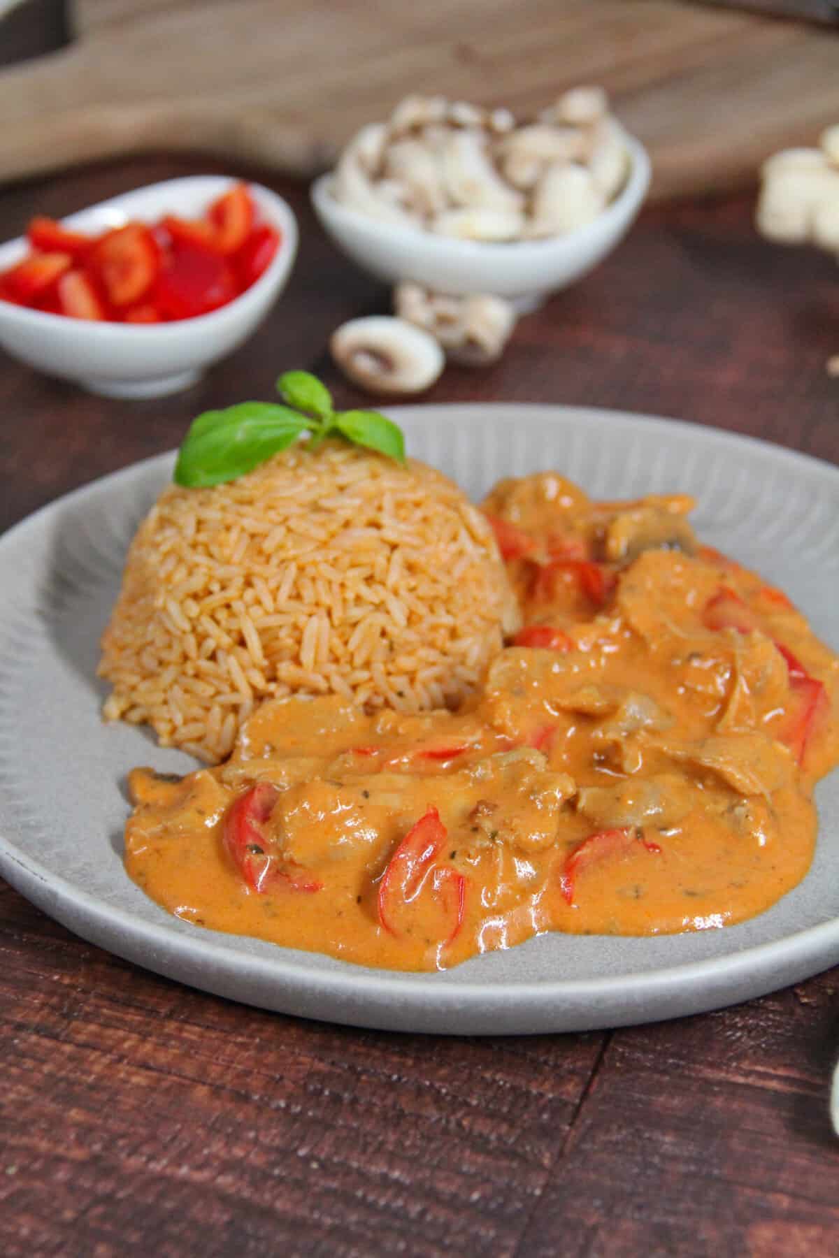 A plate of chicken gyros with bell peppers, mushrooms, and rice.