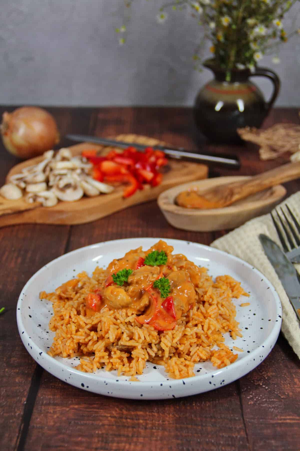 A plate of chicken gyros with bell peppers, mushrooms, and rice.