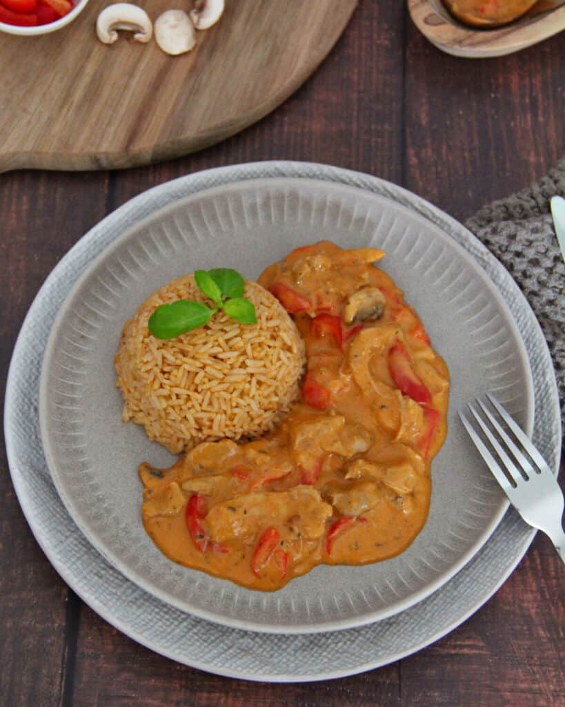 A plate of chicken gyros with bell peppers, mushrooms, and rice.