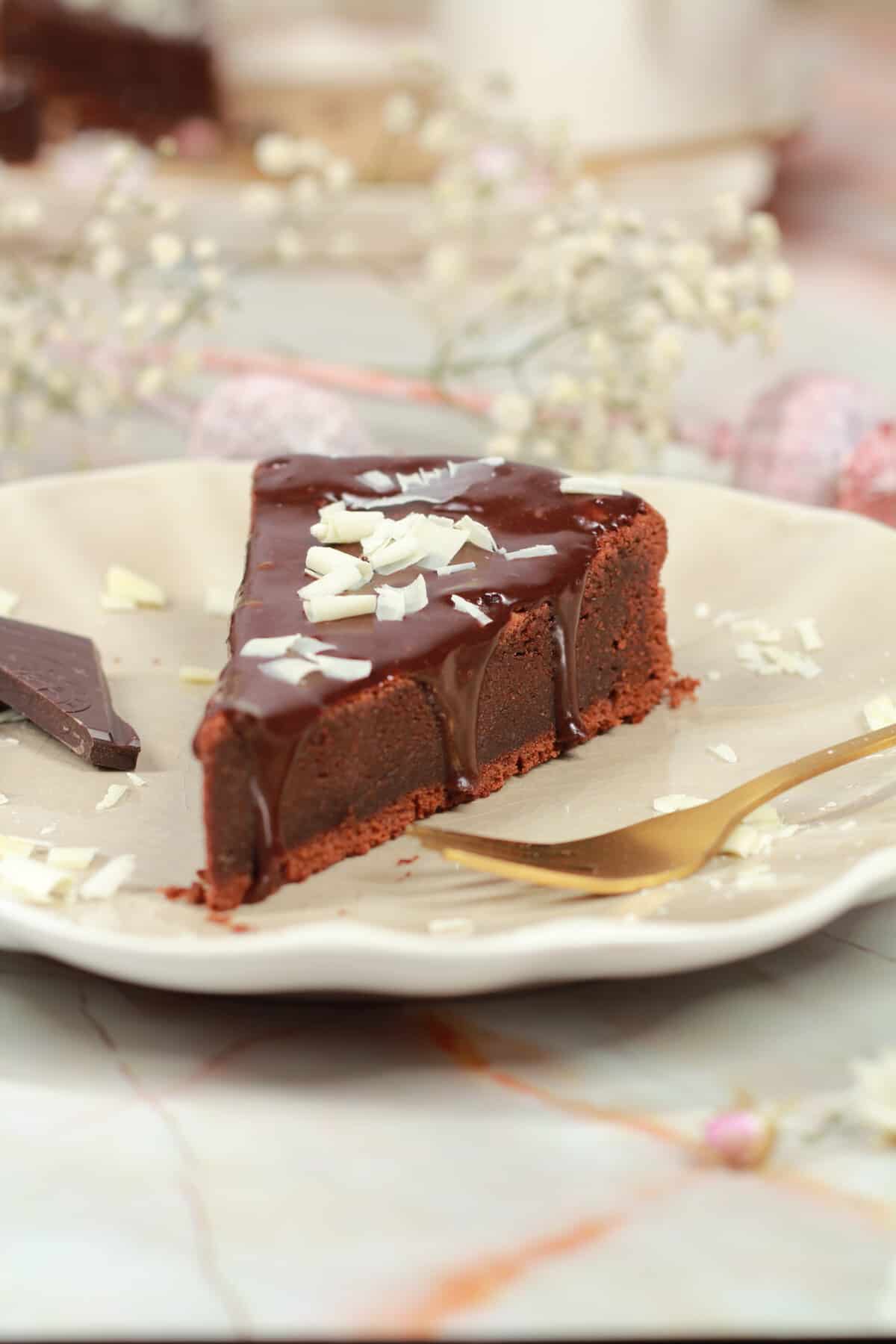 A slice of chocolate cake topped with white chocolate shavings.