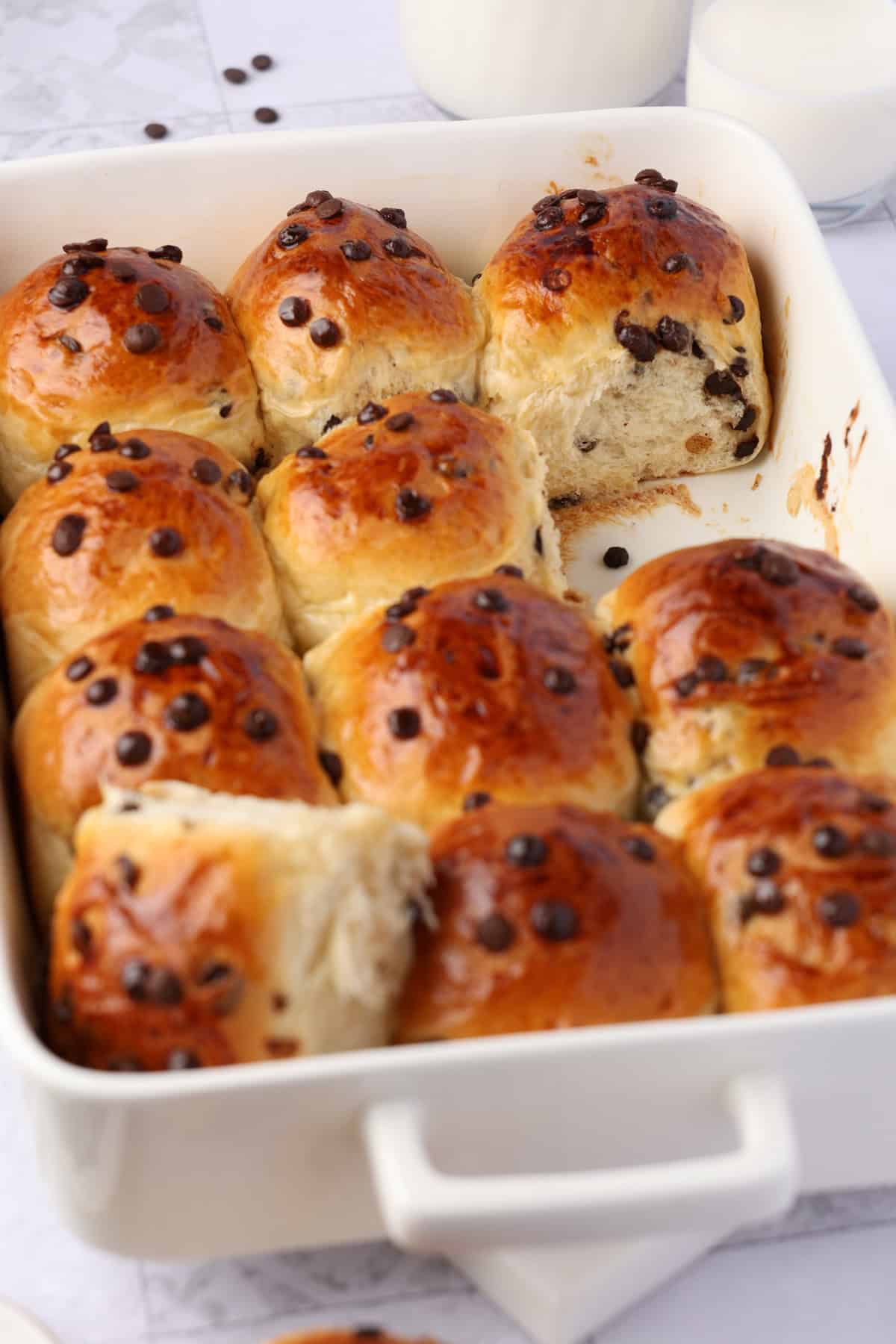 Several chocolate chip rolls in a white rectangular baking dish.