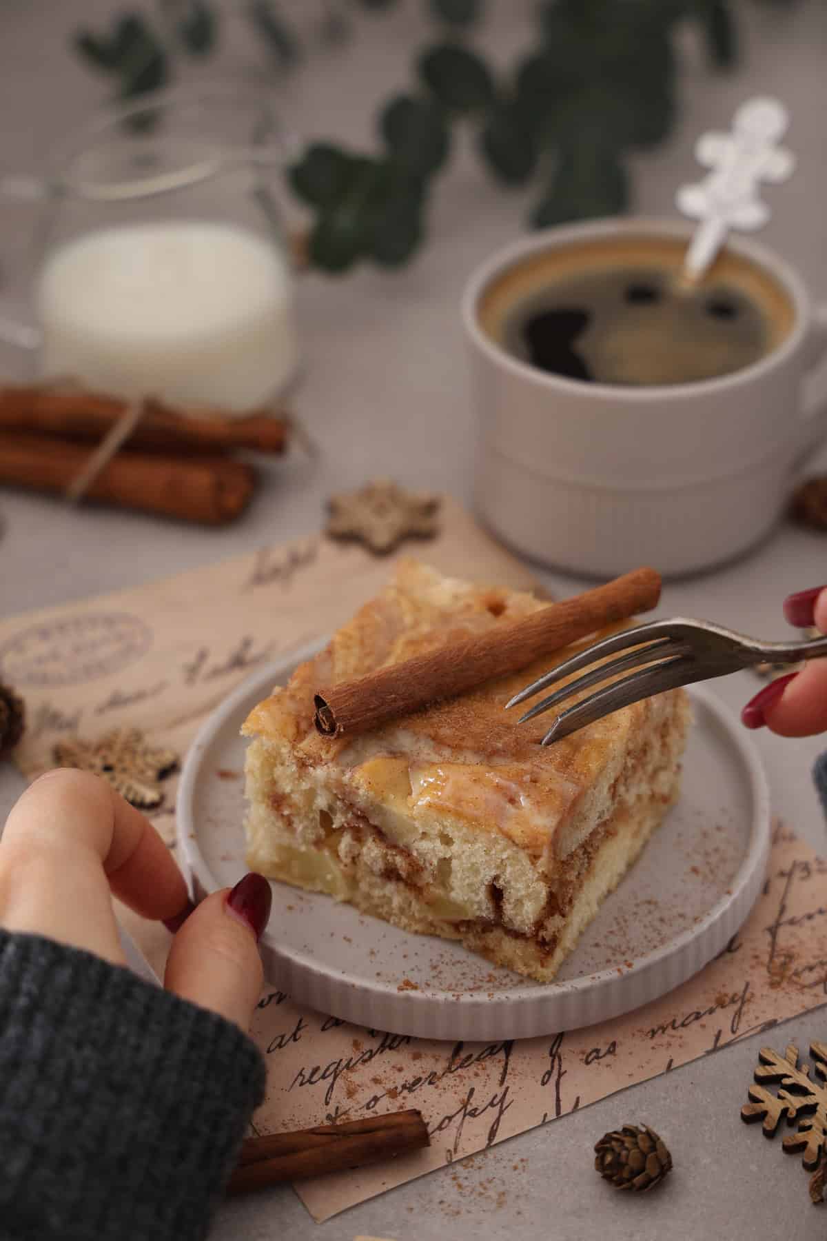 Two hands using a fork to take a bite of apple cinnamon roll cake.