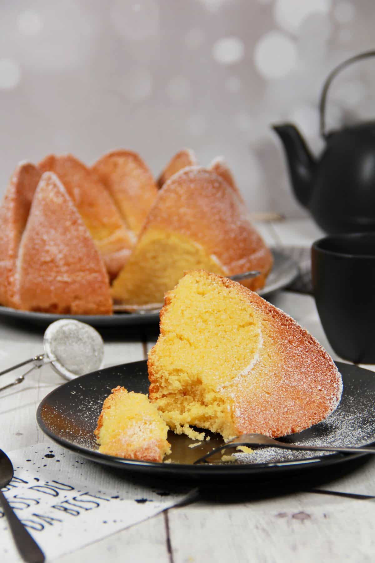 A sliced German egg liqueur cake on a dark platter with a slice served on a plate nearby.