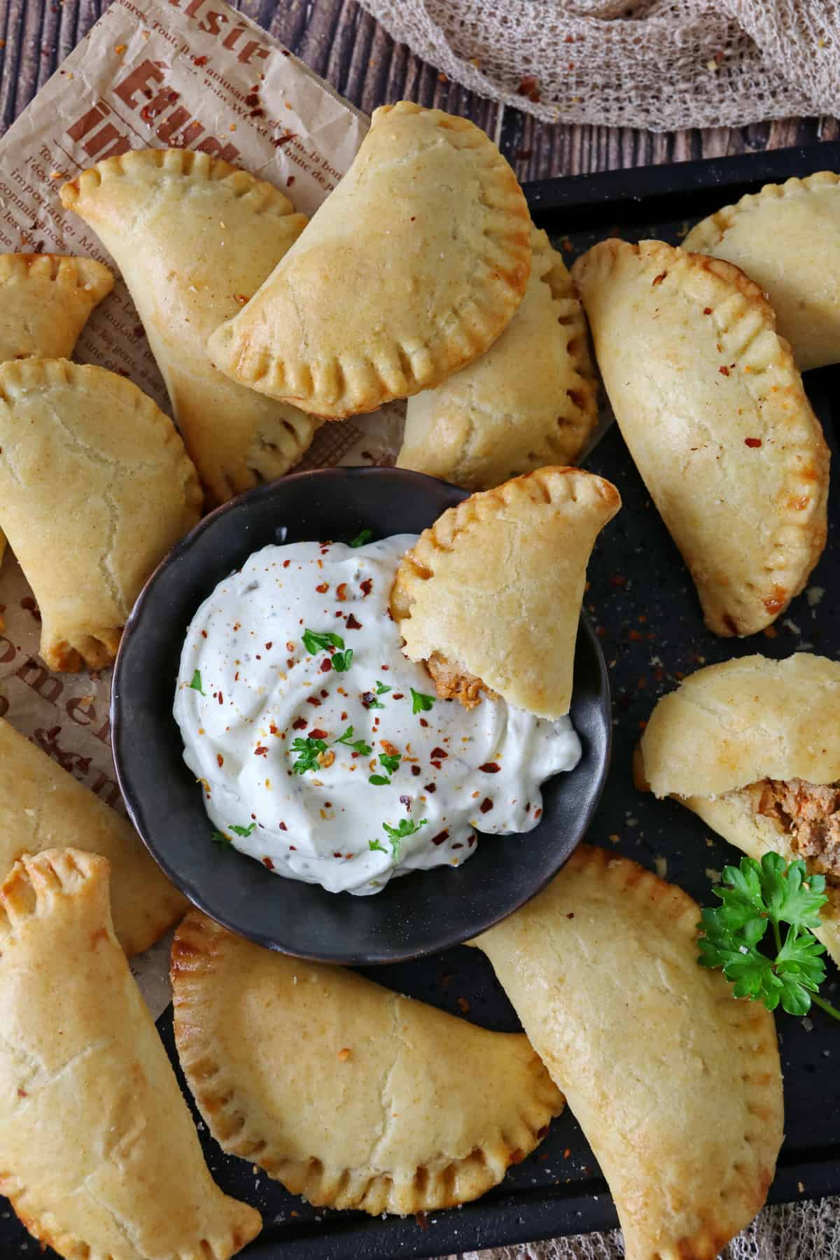 A close-up of a plate of empanadas with a small bowl of dip in the center.