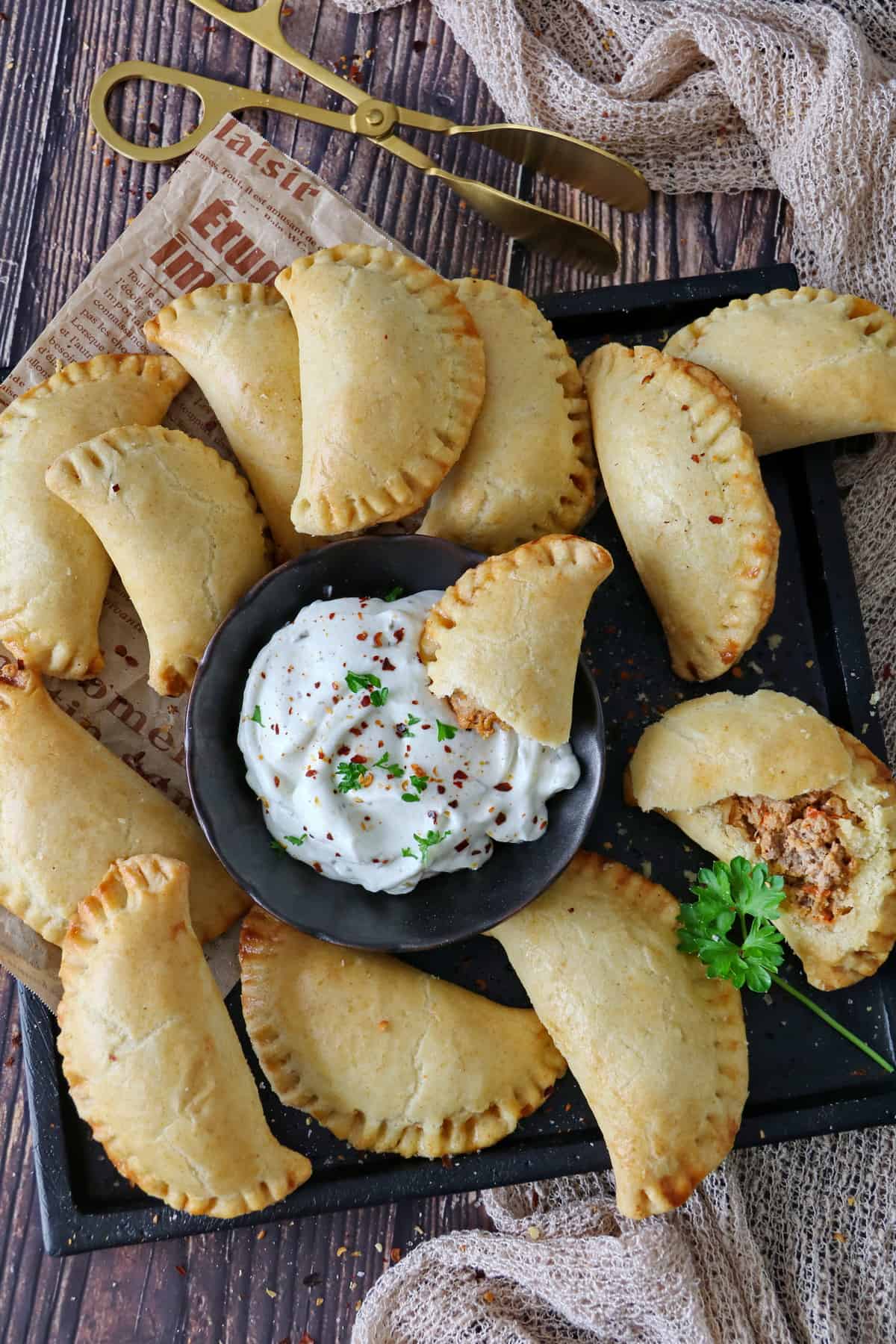 A plate of fresh empanadas with a small dipping bowl in the center.