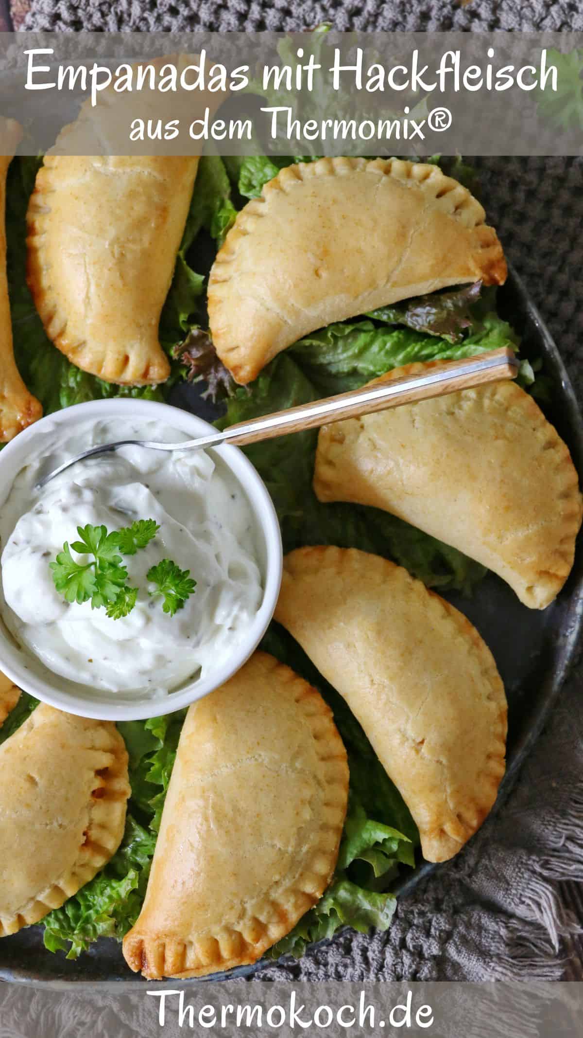 A plate of empanadas arranged in a circle over lettuce with a small bowl of dipping sauce in the center.