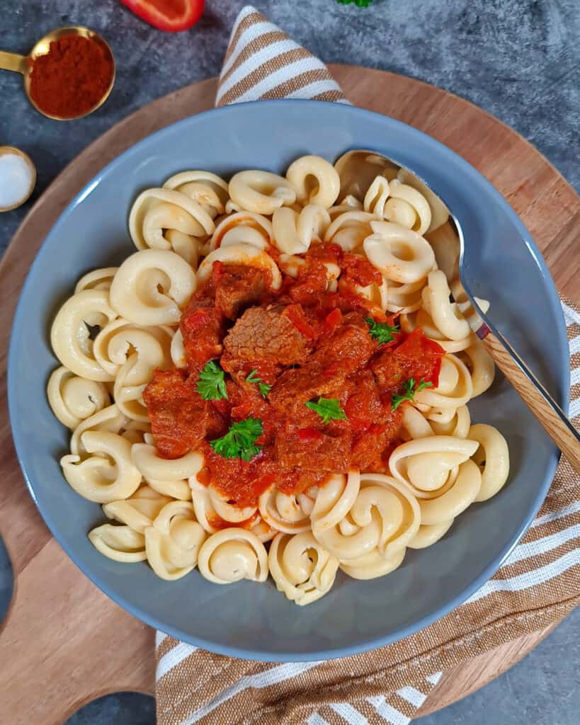A deep gray plate with beef goulash with bell peppers.
