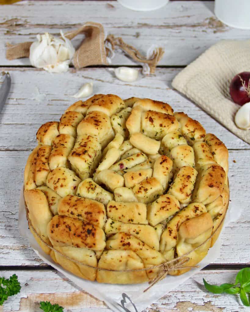 A round herb pull-apart bread surrounded by decorations.