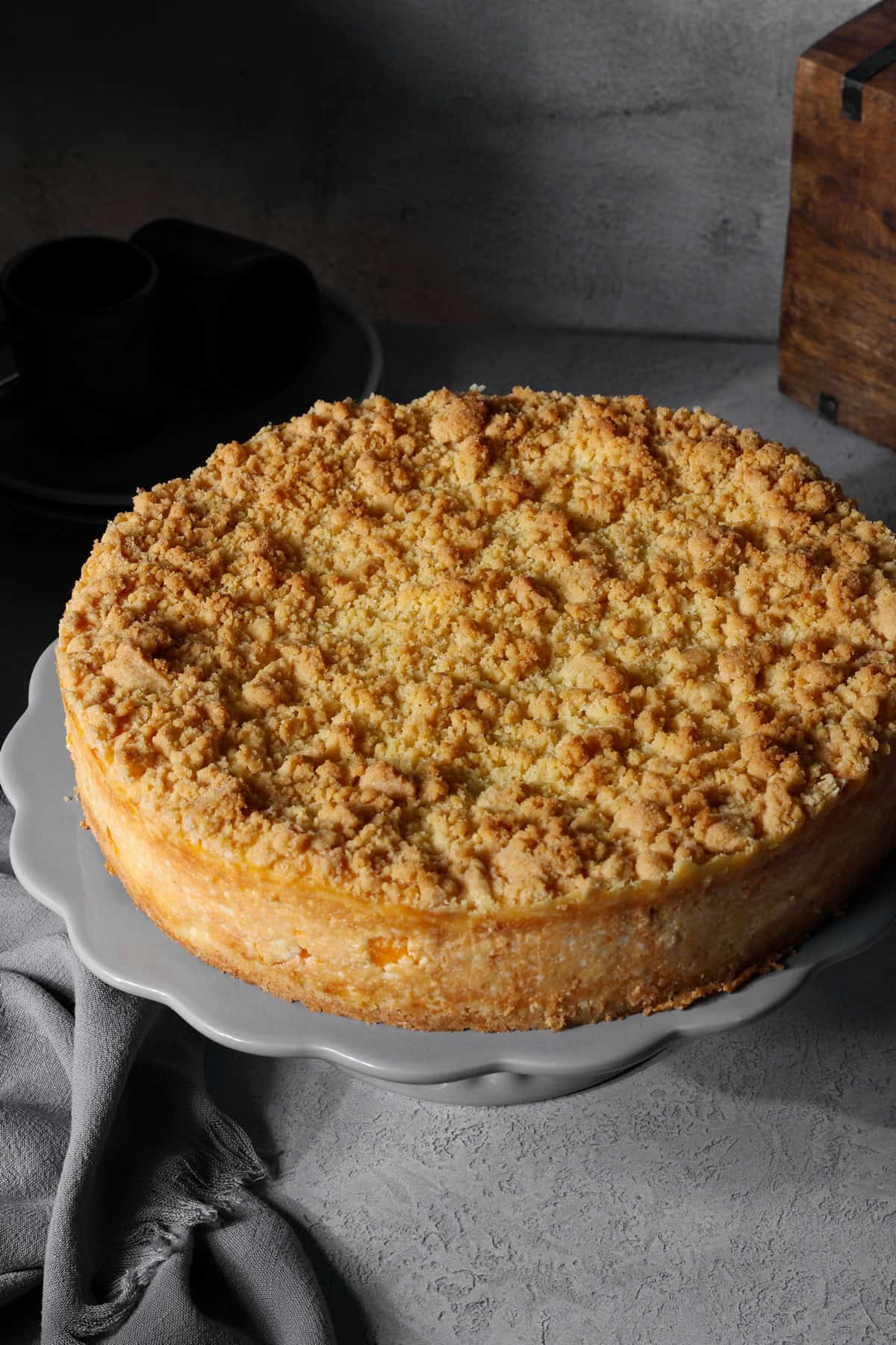 A mandarin sour cream crumb cake on a round serving tray.