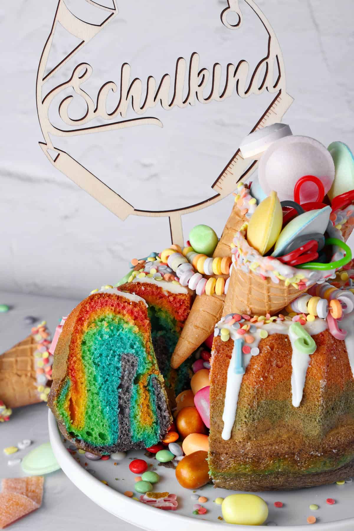 A sliced, beautifully decorated rainbow bundt cake.