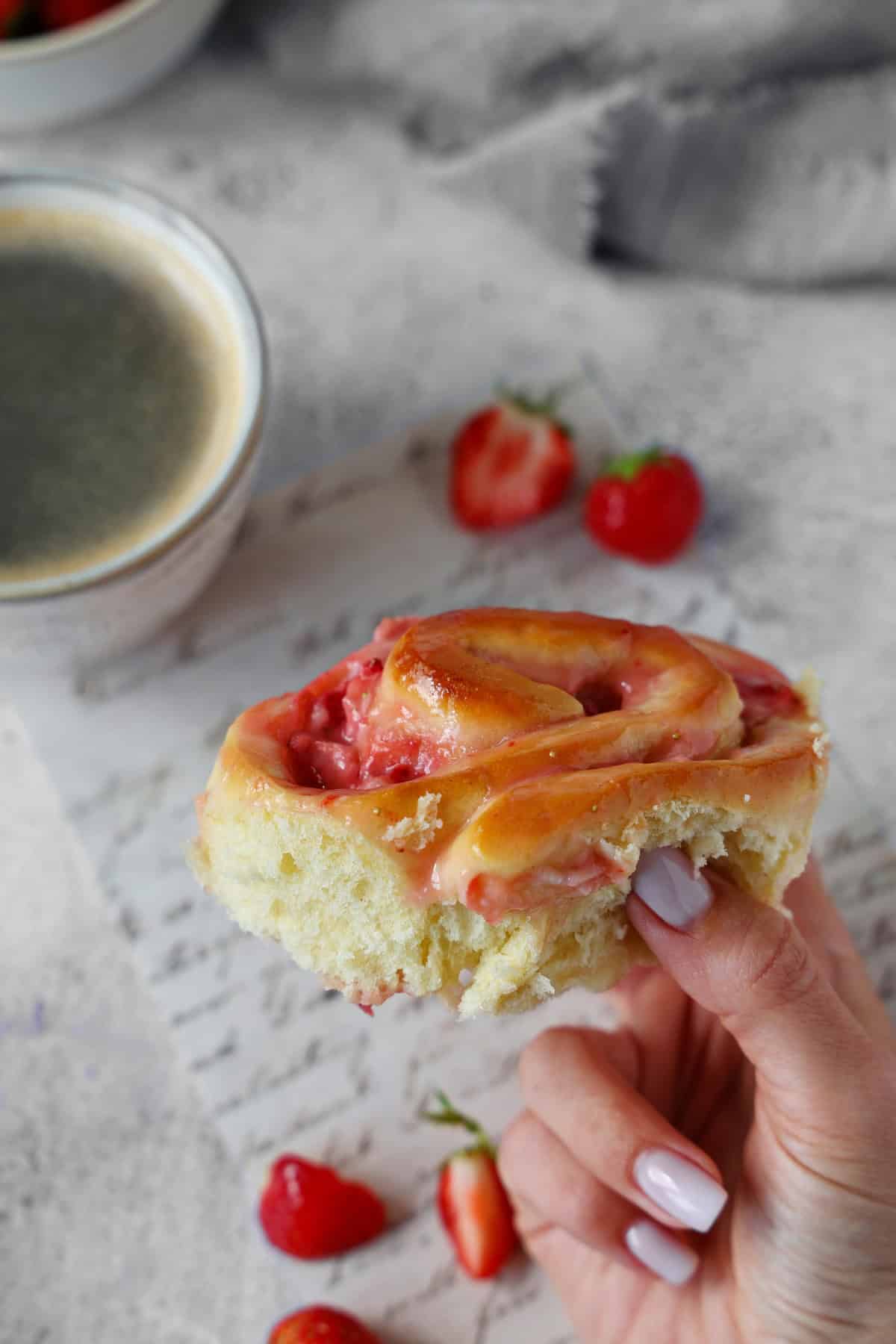 A hand holding a strawberry roll.