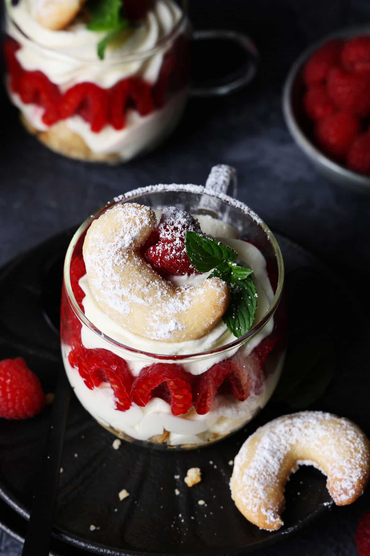 Top-down view of a glass filled with vanilla crescent cookie and raspberry dessert.