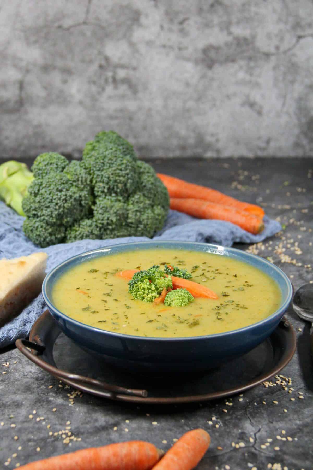 A bowl of creamy potato soup garnished with fresh broccoli and carrots.