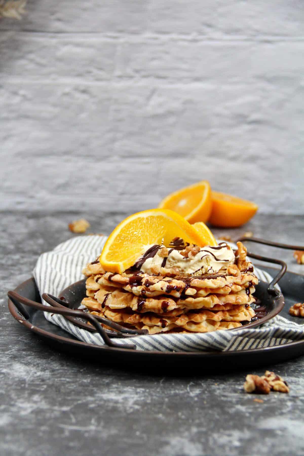 Waffles topped with vanilla ice cream, walnuts, and an orange slice.