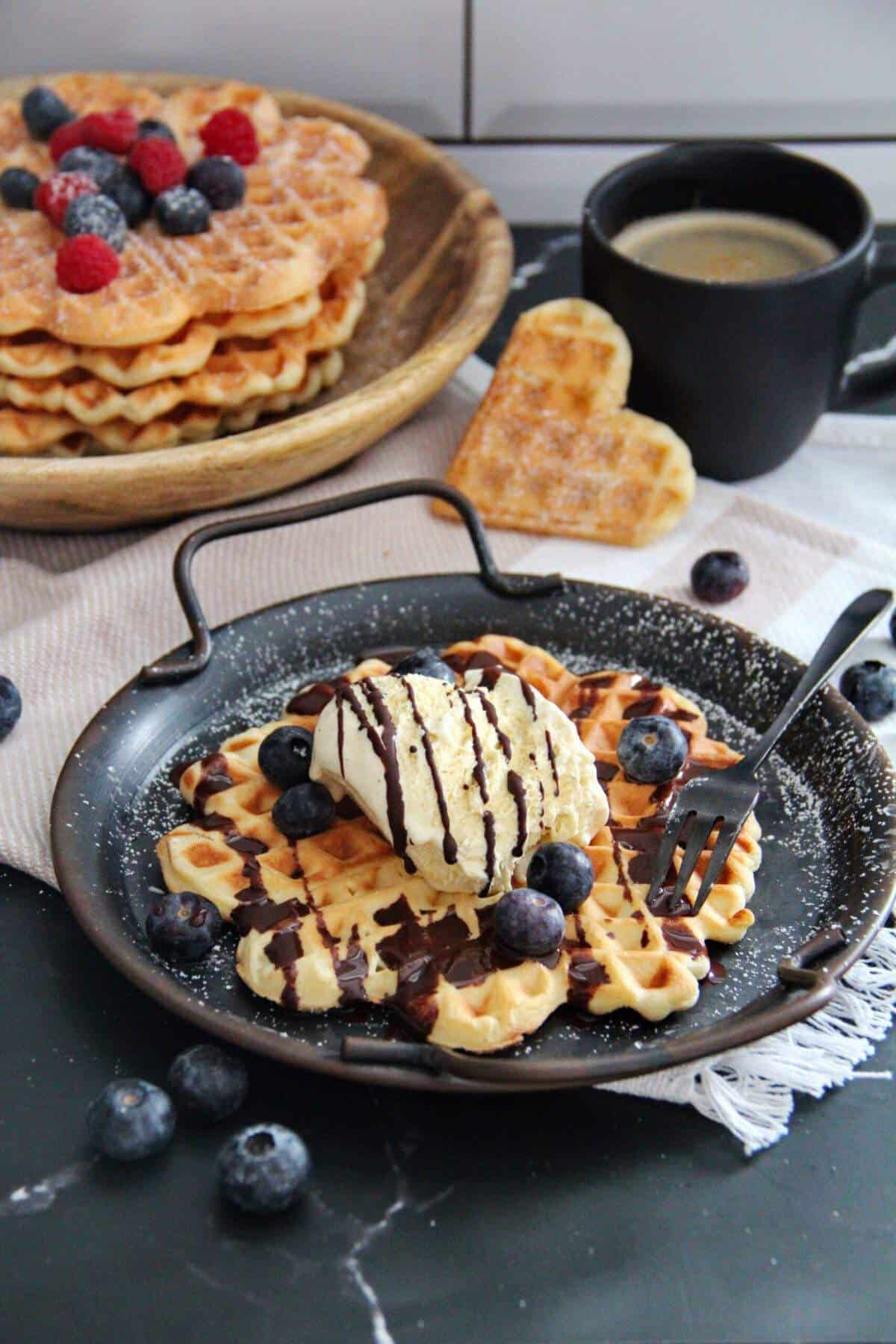 Crispy waffles made from an easy recipe, served with vanilla ice cream, chocolate sauce, and fresh blueberries.