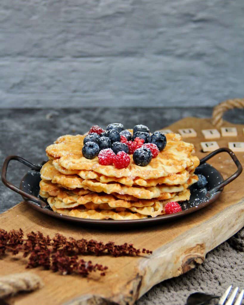 A decoratively arranged bowl with a stack of waffles topped with berries.